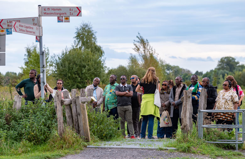Group of people in a nature reserve. On the left side of the picture there are signs for hikers and cyclists.